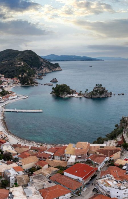 Parga city, Greece. Aerial drone view of the Castle ruins, the traditional town building and the islands in the bay, cloudy blue sky background.